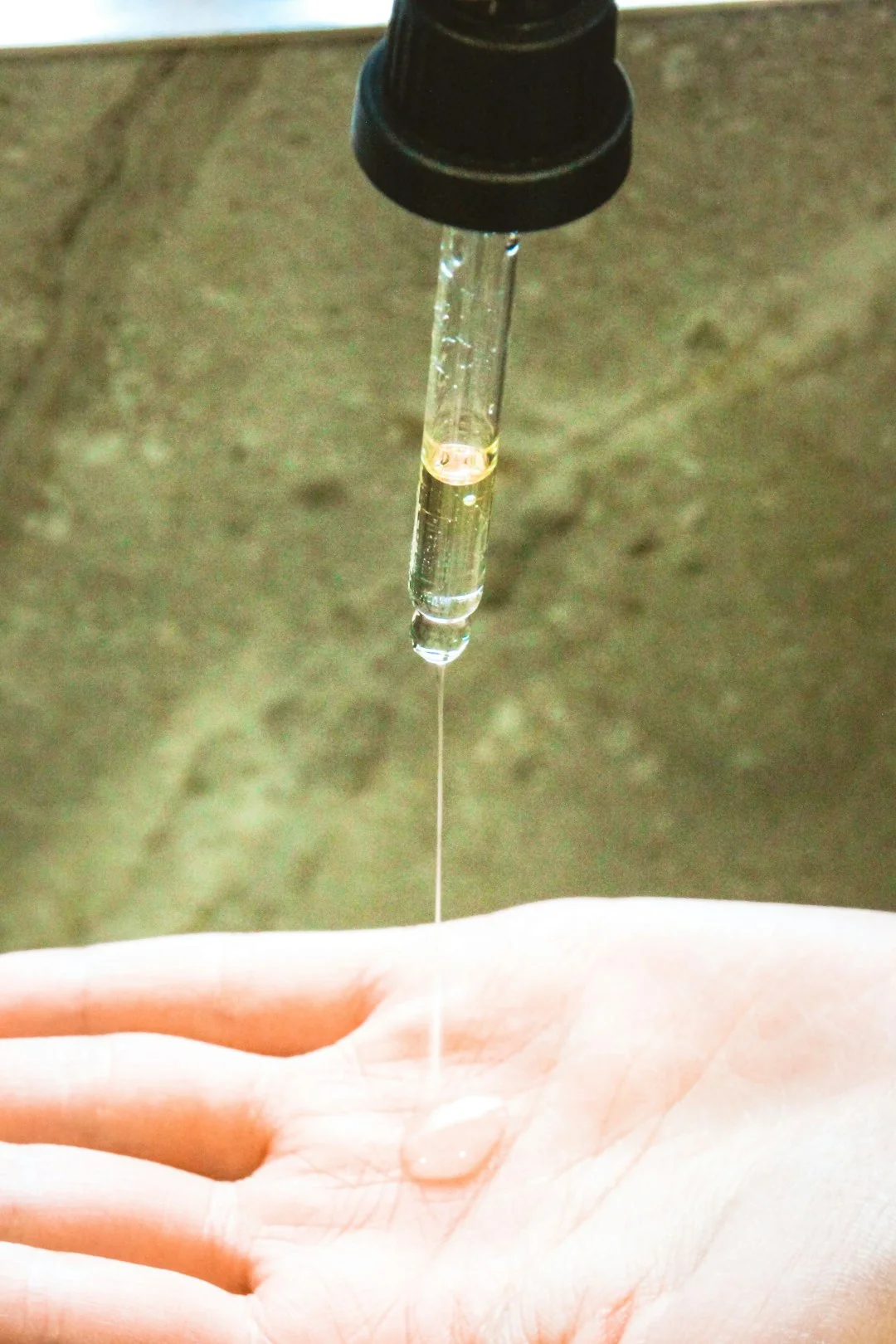 Close-up of gloved hands disinfecting a remote control with a cloth and spray bottle.
